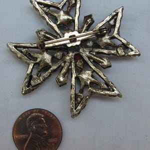 Puede incluir: Broche vintage dorado en forma de estrella con cierre de alfiler. El broche presenta un dise&ntilde;o calado con peque&ntilde;os acentos coloridos. Una moneda est&aacute; al lado del broche para comparar el tama&ntilde;o.
