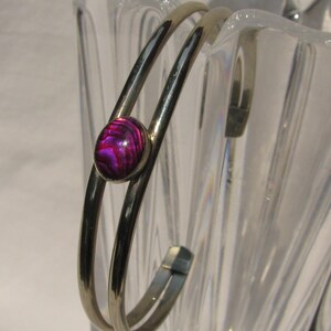 May include: A silver double bangle bracelet with a round, purple abalone shell inlay.