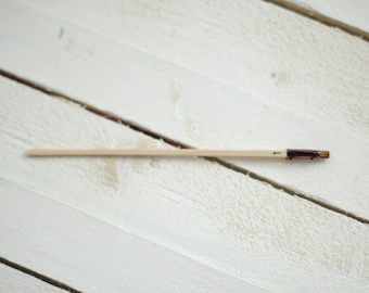 May include: A wooden skewer with a brown tip, labeled with the number "1" on a white wooden surface.