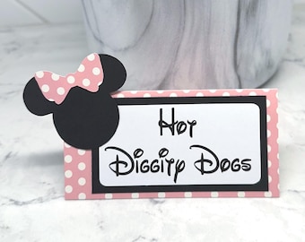 May include: A pink and white polka dot card with the text "Hey Diggity Dogs" in black script. A black Minnie Mouse head with a pink polka dot bow is attached to the card. The card is on a white and grey marble surface.