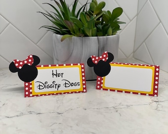 May include: Two place cards featuring Mickey Mouse ears and bows. The cards have a red and white polka dot border, a yellow inner border, and a white central area. One card says "Hot Diggity Dogs".