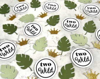 May include: Green and white confetti with gold crowns and circles that say "two wild" in black text.
