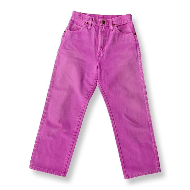 May include: A pair of high-waisted, straight-leg jeans in a vibrant magenta hue. The jeans feature classic five-pocket styling, a button and zipper closure, and belt loops. The denim appears to be pre-washed for a faded look.