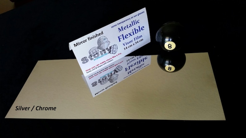 May include: A sheet of silver chrome metallic flexible visor film, 14 inches by 34 inches, with a mirror finish. The film is shown on a black surface with a black 8-ball and its reflection.