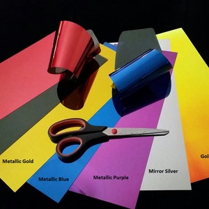 May include: Assortment of colored vinyl sheets for crafting, including metallic red, black, metallic gold, metallic blue, metallic purple, mirror silver, and gold iridium. A pair of scissors is also included.