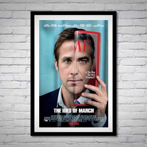 May include: A movie poster for the film "The Ides of March" featuring George Clooney, Ryan Gosling, and Philip Seymour Hoffman. The poster has a blue background with a red and white magazine cover featuring Ryan Gosling's face. The text on the magazine cover reads "Is This Man Our Next President?" The poster also includes the text "The Ides of March" and "This Fall."