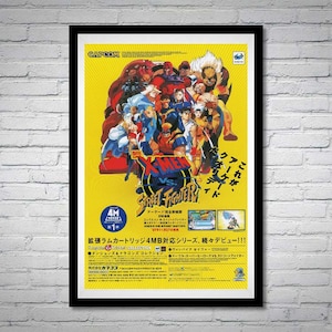 May include: Framed poster featuring the artwork for the video game X-Men vs. Street Fighter. The poster has a yellow background with multiple characters in action poses. The game's title is prominently displayed in a stylized font, with Japanese text on the right.