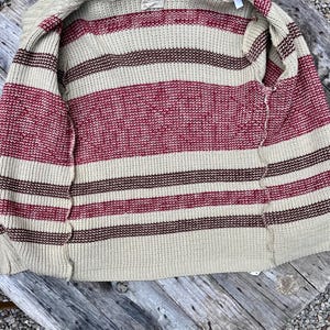 May include: A beige striped cardigan with red and brown stripes. The cardigan is unbuttoned and laid flat on a wooden surface.