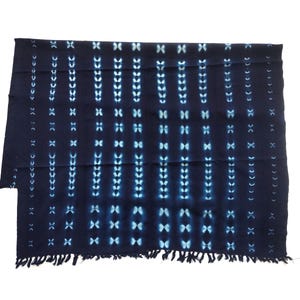 May include: A dark blue textile with a repeating pattern of white and light blue shapes. The design includes vertical lines of small, connected shapes and larger, cross-like motifs. The bottom edge has a fringe.
