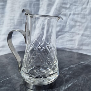May include: A clear glass jug with a cut glass design and a silver metal handle and lid.