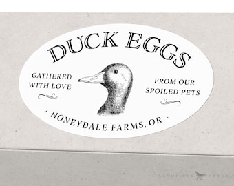 May include: White oval sticker with black text that reads "Duck Eggs", "Gathered with Love", "From Our Spoiled Pets", and "Honeydale Farms, OR". A black and white illustration of a duck's head is in the center of the sticker.