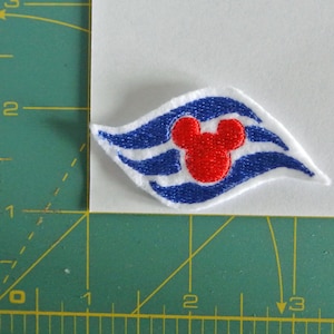 May include: A blue and white embroidered patch with a red Mickey Mouse head in the centre. The patch features a stylised wave design.