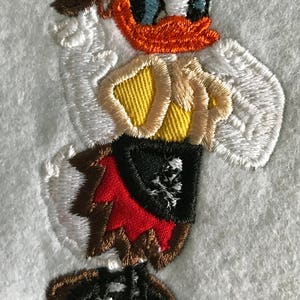 May include: Embroidered patch of a cartoon duck wearing a brown hat, red skirt, and black shoes. The duck is holding a yellow and brown object.