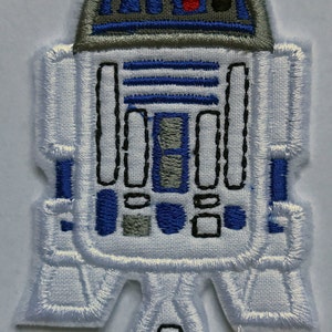 Op de afbeelding: Witte geborduurde patch van een Star Wars-personage, R2-D2, met blauwe en grijze details. De patch is ongeveer 7,5 cm hoog.