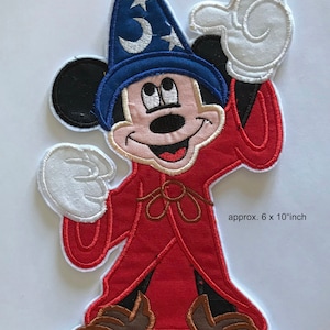May include: An embroidered iron-on patch of Mickey Mouse dressed as a wizard. He is wearing a blue hat with a crescent moon and star, a red robe, and brown shoes. The patch is approximately 6 by 10 inches.
