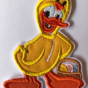 May include: Yellow embroidered iron-on patch of a duck wearing a yellow raincoat and carrying a brown basket with colourful eggs.