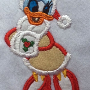 May include: Embroidered Christmas applique of a cartoon duck wearing a Santa hat and holding a holly sprig. The duck is white with a red and white Santa hat, red shoes, and a yellow beak.