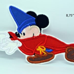 Könnte beinhalten: Ein gestickter Bügel-Patch mit Mickey Mouse als Zauberer. Er trägt einen blauen Hut, eine rote Robe und braune Schuhe. Er hält einen Zauberstab und es kommt weißer Rauch heraus. Der Patch ist 8,75 Zoll breit.