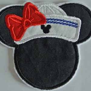 Könnte beinhalten: Ein gestickter Patch in Schwarzweiß von einer Comic-Maus, die einen weißen Matrosenhut mit einer roten Schleife trägt. Die Maus hat schwarze Ohren und eine schwarze Nase.
