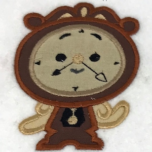 May include: Brown and beige embroidered iron-on patch of a cartoon clock character with a smiling face. The patch is approximately 3 by 4 inches.