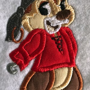 May include: Embroidered patch of a cartoon chipmunk wearing a red shirt, a black pirate hat, and brown trousers.