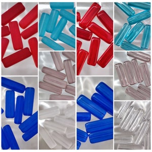 Peut inclure: Assortiment de tiges de verre colorées dans différentes couleurs, notamment rouge, bleu, blanc, gris et transparent. Les tiges sont toutes à peu près de la même taille et de la même forme, et elles sont disposées en grille.