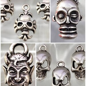 May include: A set of silver-toned metal charms featuring various skull and demon designs. The charms are detailed and have a vintage look.