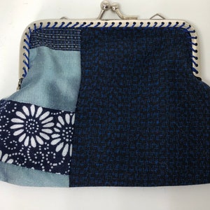 May include: A small blue and white patchwork fabric coin purse with a silver clasp.