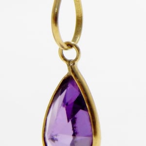 May include: A gold pendant with a teardrop-shaped amethyst gemstone.