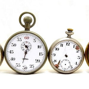 Op de afbeelding: Vier antieke zakhorloges met zilveren en gouden kastjes. De horloges hebben witte wijzerplaten met zwarte Romeinse cijfers voor de uren en zwarte wijzers. Een horloge heeft een stopwatchfunctie met een kleinere wijzerplaat voor de seconden.