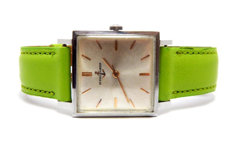 Pu&ograve; includere: Un orologio da polso vintage Ulysse Nardin con quadrante quadrato argentato e lancette e indici dorati. L'orologio ha un cinturino in pelle verde brillante. Il quadrante dell'orologio presenta il logo Ulysse Nardin.