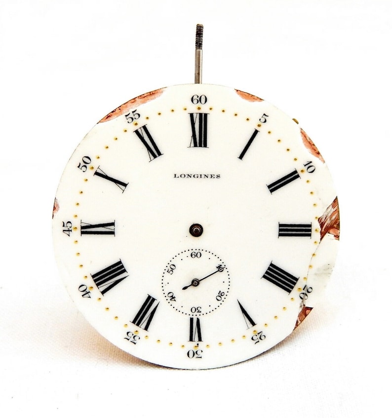 Peut inclure: Cadran d'horloge blanc avec des chiffres romains noirs pour les heures et des marques noires pour les minutes. Le cadran porte l'inscription "LONGINES" en noir en haut. Le cadran est l&eacute;g&egrave;rement endommag&eacute;.