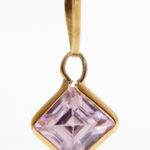 May include: A gold pendant with a square-shaped pink gemstone.