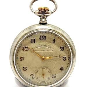 May include: A vintage silver pocket watch with a gold crown and hands. The watch face is a light beige colour with black numerals and the text "CHRONOMETRE ORGEMONT WATCH". A smaller seconds dial is at the bottom.