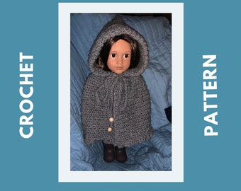 May include: A gray hooded crochet cape with wooden buttons for a doll. The doll is wearing the cape and has brown hair and brown eyes.