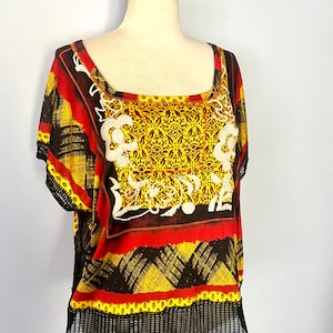 May include: A black, red, and yellow patterned shirt with white embroidery and a crocheted trim.