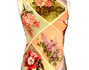 May include: A sleeveless top with a floral print. The print features a variety of flowers in shades of pink, purple, and green. The top is made of a lightweight fabric and has a relaxed fit.