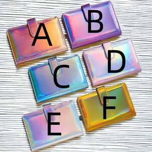 May include: Six iridescent binders with letters A through F on the front. The binders are all different colors, including pink, purple, blue, and gold.