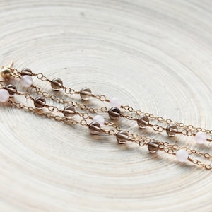 May include: A pair of long, gold chain earrings with alternating brown and pink beads.