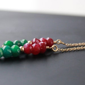May include: A gold chain necklace with green and red gemstone beads. The beads are faceted and have a polished finish.