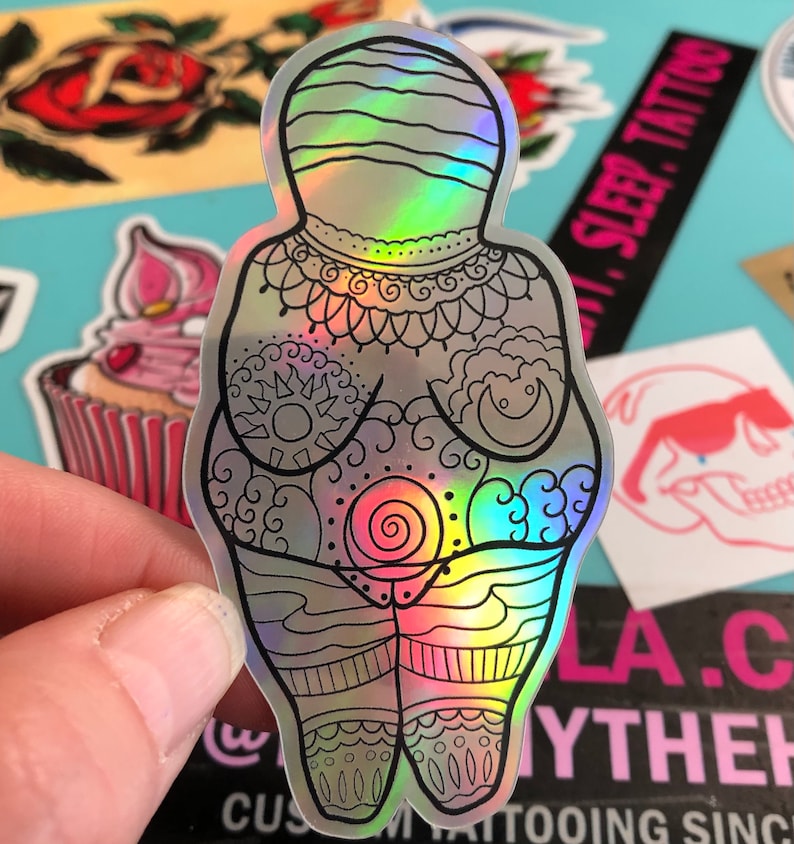 Puede incluir: Una pegatina hologr&aacute;fica de una figura femenina con intrincados dise&ntilde;os de l&iacute;neas. La figura est&aacute; de pie con los brazos a los lados y tiene un dise&ntilde;o en espiral en el centro de su torso. La pegatina es iridiscente y tiene un brillo arco&iacute;ris.