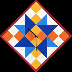 May include: A diamond-shaped wall clock featuring a geometric star pattern in shades of blue, orange, yellow, and white. The clock has a thin red frame and black hands centred on the face. The surface displays a textured, painted wood finish.