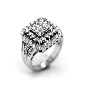 Puede incluir: Un anillo de plata con un racimo de diamantes de forma cuadrada en el centro. El anillo tiene una banda con varias filas de diamantes más pequeños.