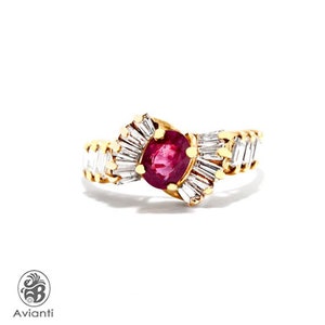 Op de afbeelding: Een gouden ring met een rode robijn-edelsteen omringd door kleinere diamanten. De ring heeft een uniek ontwerp met de diamanten in een waaiervorm gezet.