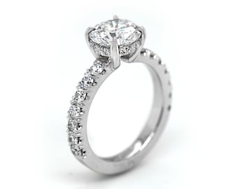 May include: A silver engagement ring with a large, round, clear center stone and a band of smaller, clear stones.