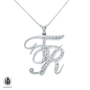 May include: A silver necklace with a pendant featuring the letters "FR" set with diamonds. The letters are in a cursive script.