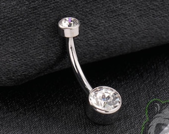 May include: A curved barbell belly button ring featuring a polished silver-tone metal shaft with a smaller clear round gemstone at the top and a larger clear round gemstone at the bottom, both set in a smooth metal bezel setting.