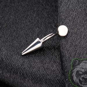 May include: A silver-toned curved barbell body jewelry piece featuring a flat circular disc at one end and a pointed cone-shaped spike at the other end. The metal has a polished, reflective finish, showcasing a smooth, minimalist design.