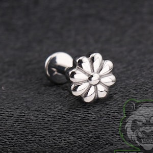 May include: A silver-toned metal body jewelry stud featuring a flat, circular back and a front-facing decorative element shaped like a flower with eight rounded petals surrounding a central raised dot, polished to a high-shine metallic finish.