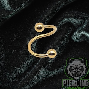 May include: A gold-colored spiral barbell piercing with two ball ends. The jewelry is displayed on a dark green velvet surface. The logo for Piercing Panda is in the bottom right corner.